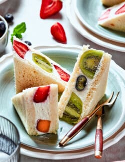 Slices of fruit sando on a plate with a fork.