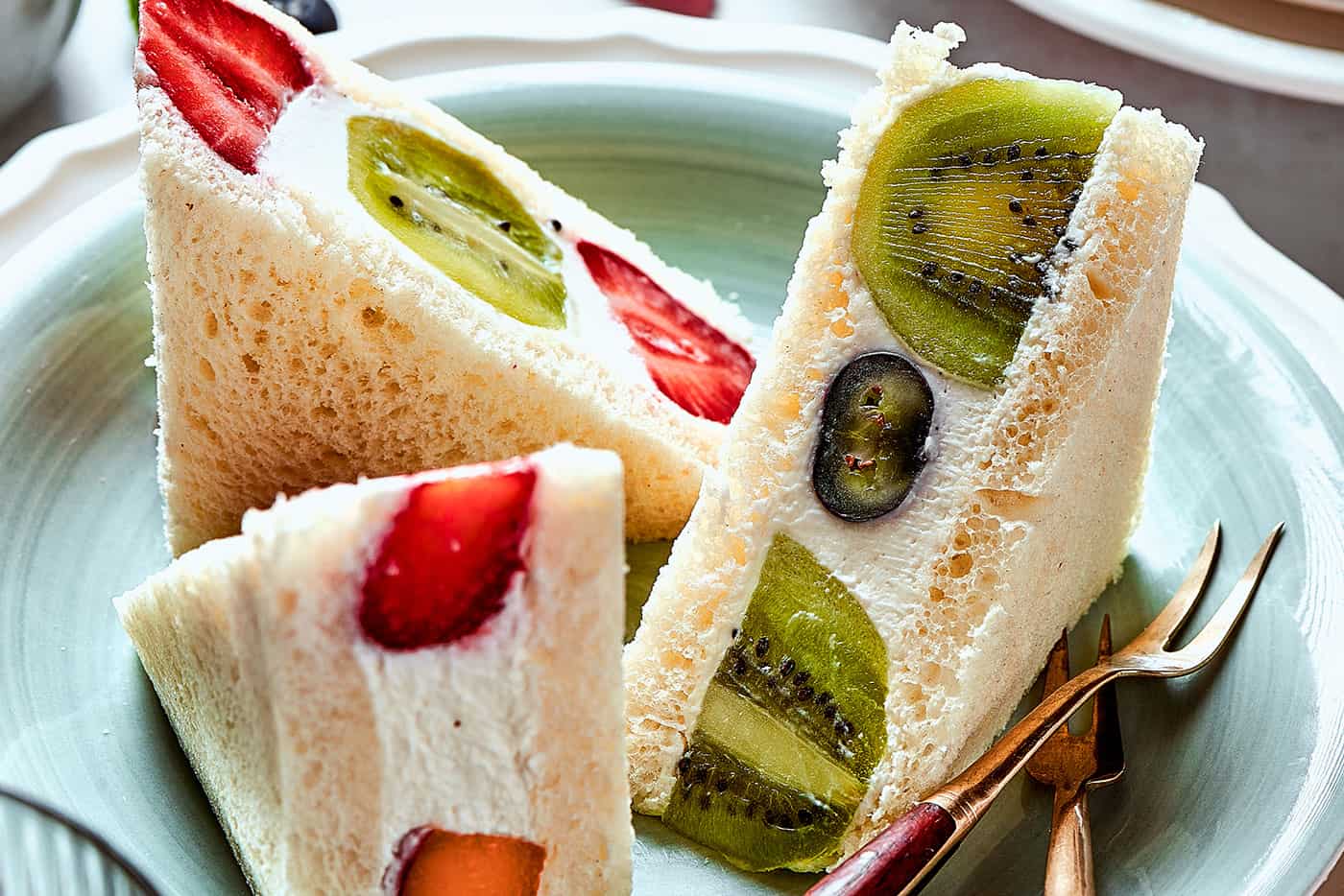 sandwich triangles made with soft bread, fluffy whipped cream, and fresh fruit