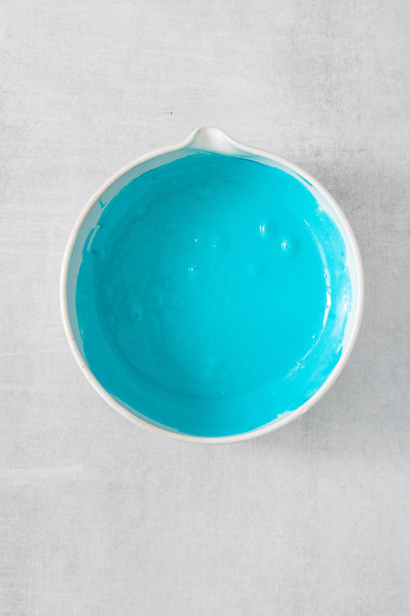 A bowl of frosting colored with blue food coloring.