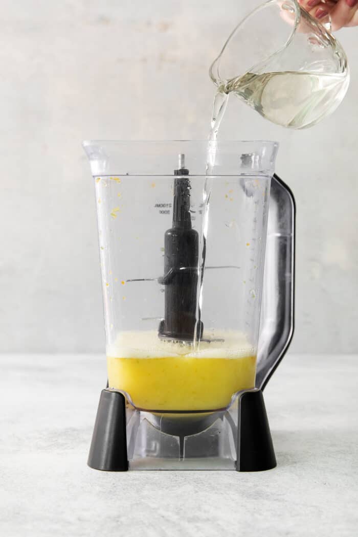 Simple syrup is poured into a blender of juice.