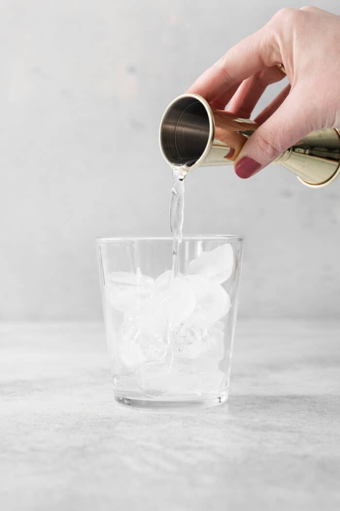 Vodka is poured into a glass of ice.