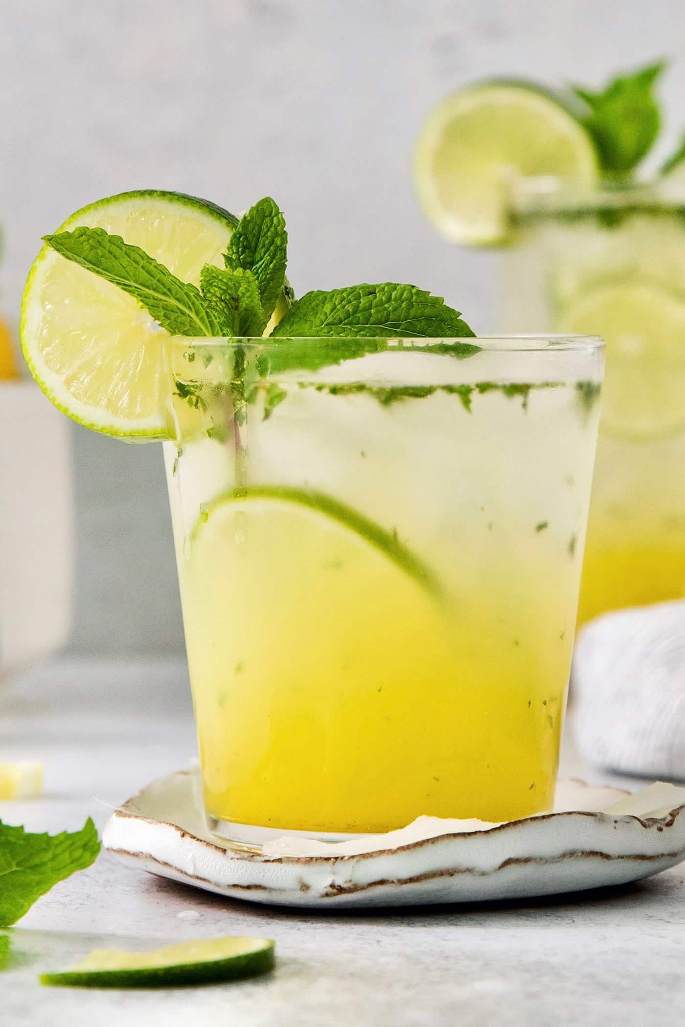 A close up of a bootleg cocktail in a glass garnished with mint leaves and lime.