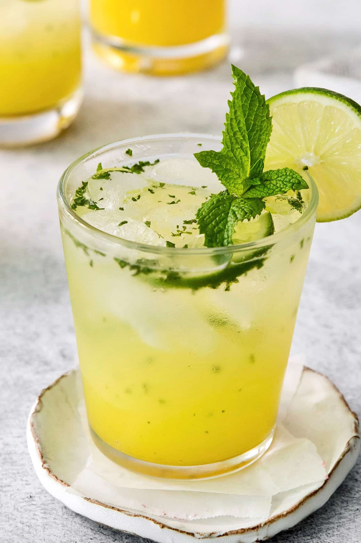 A close up of a bootleg cocktail in a glass garnished with mint leaves and lime.