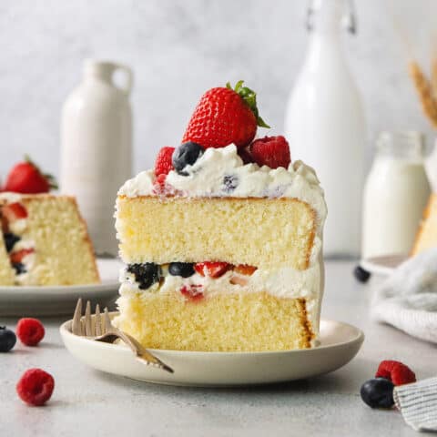 A slice of berry Chantilly cake on a plate with a fork.