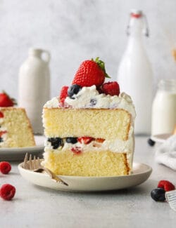 A slice of berry Chantilly cake on a plate with a fork.