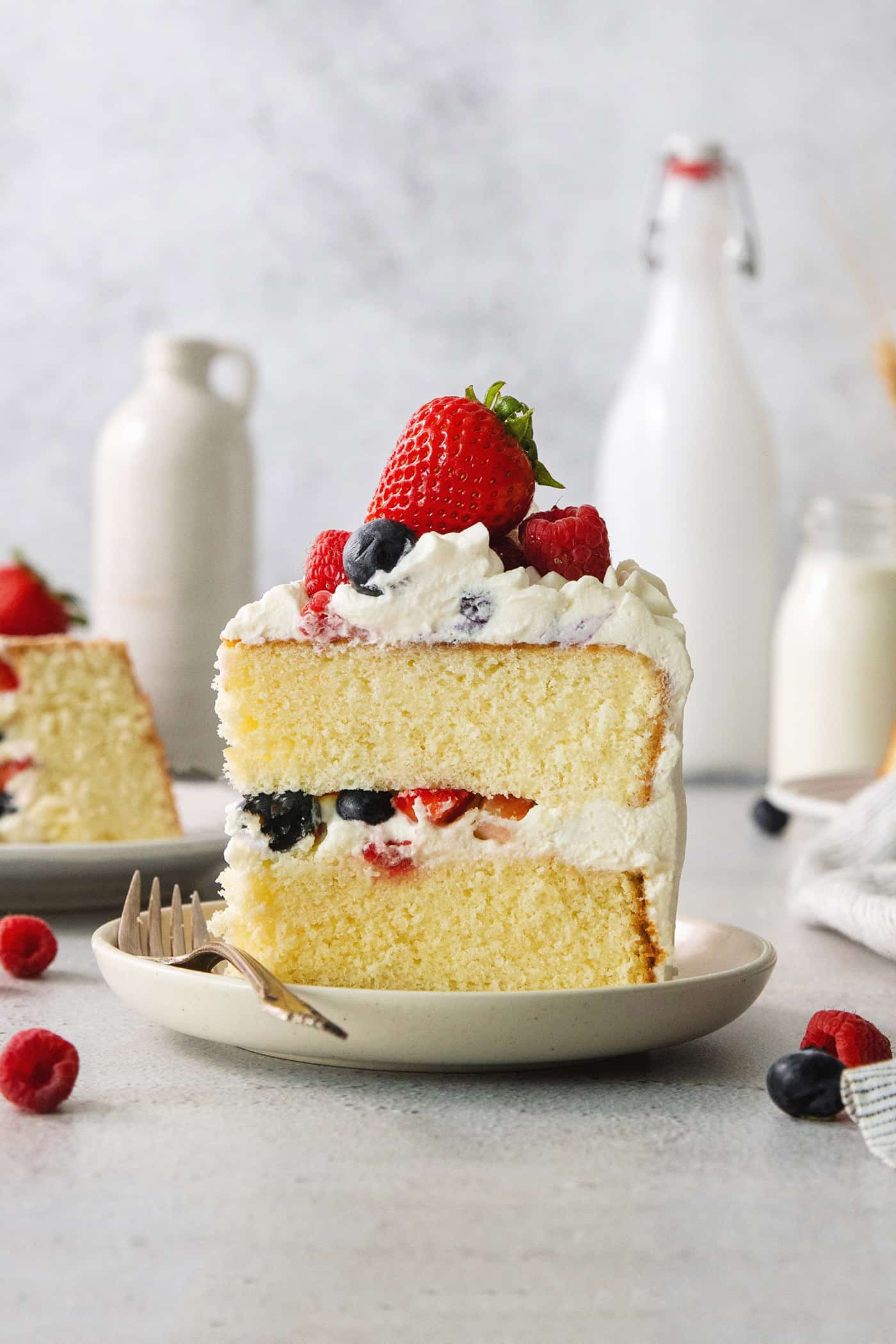 A slice of berry Chantilly cake on a plate with a fork.