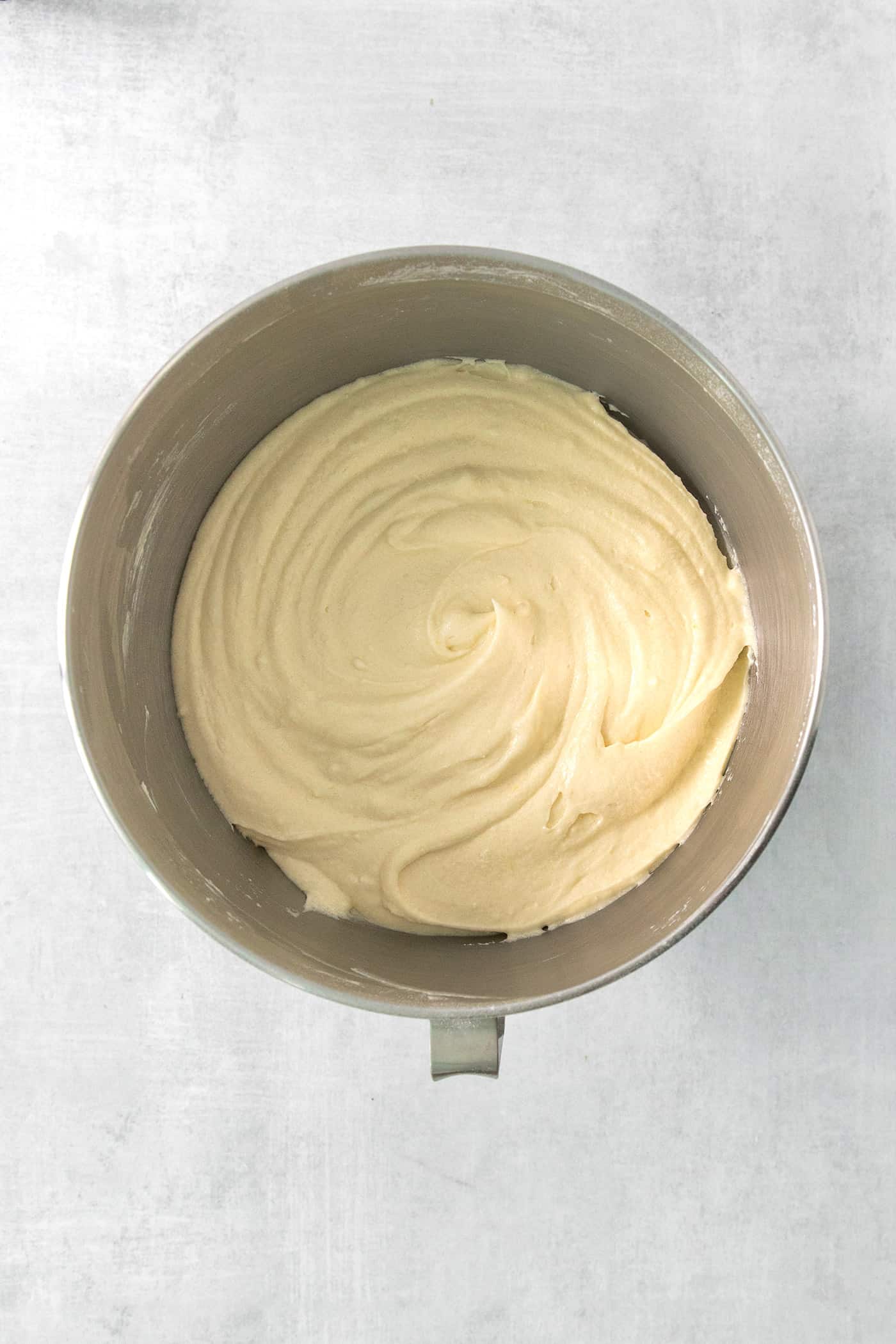 Cake batter is shown in the bowl of a stand mixer.