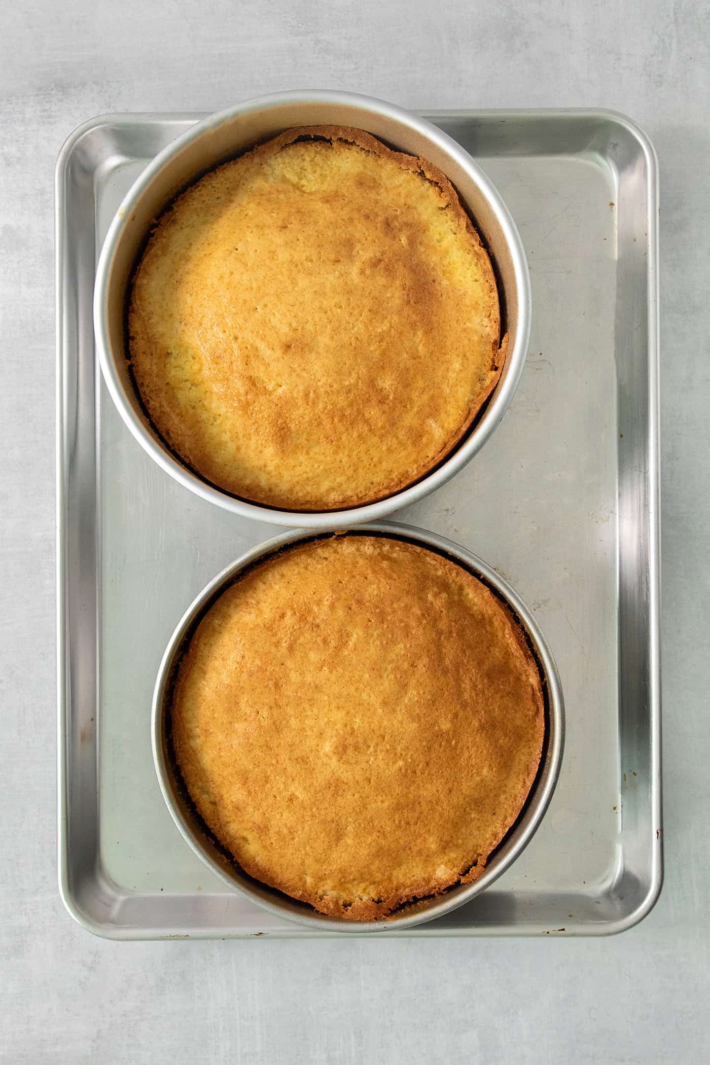 Two baked cake layers on a baking sheet.