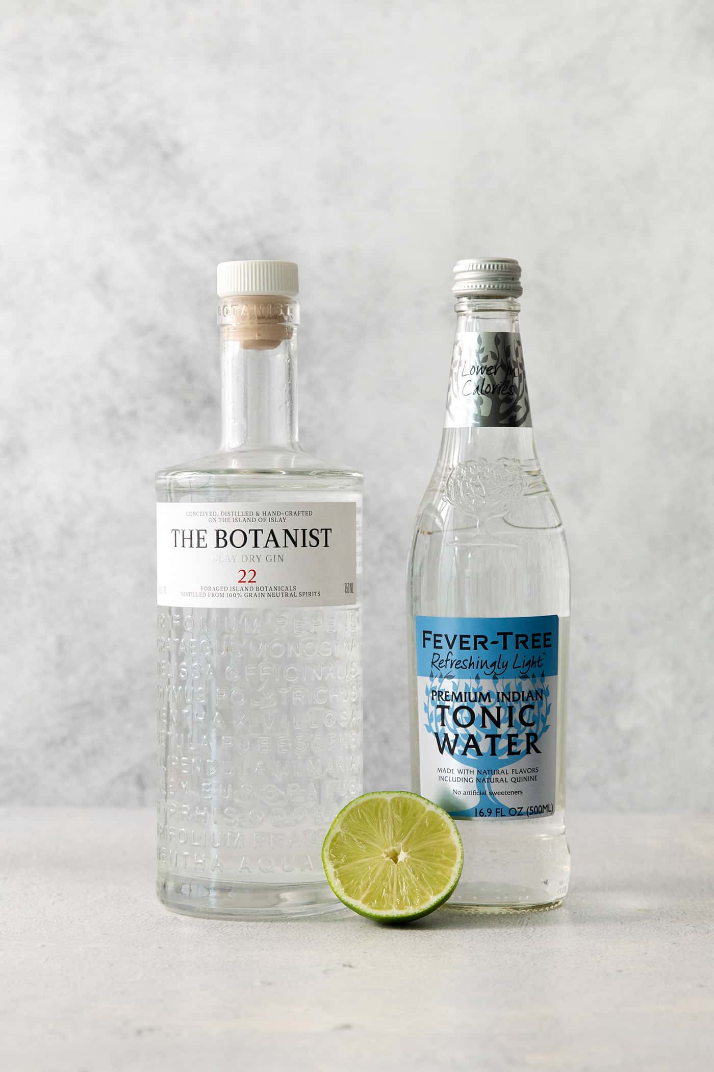 Ingredients for gin and tonic: lime, gin, and tonic water.
