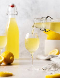 A bottle pours limoncello into a glass.