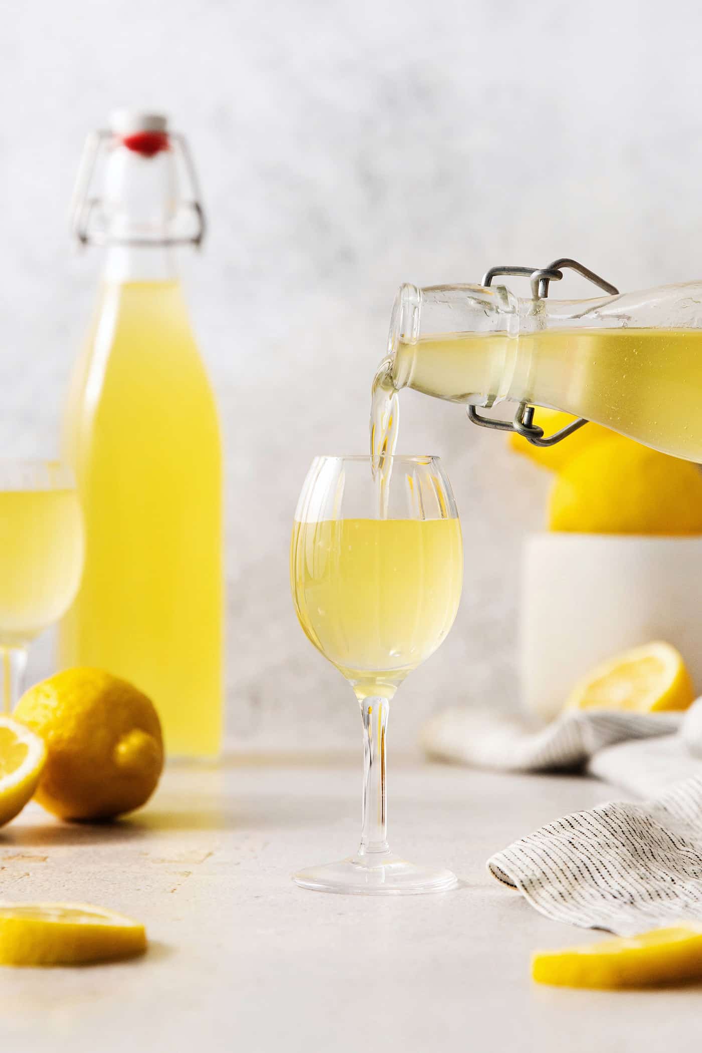 A bottle pours limoncello into a glass.