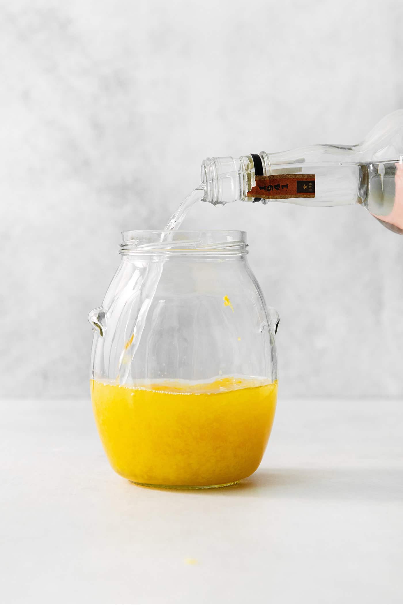 Vodka is poured into a jar of lemon zest to make limoncello.