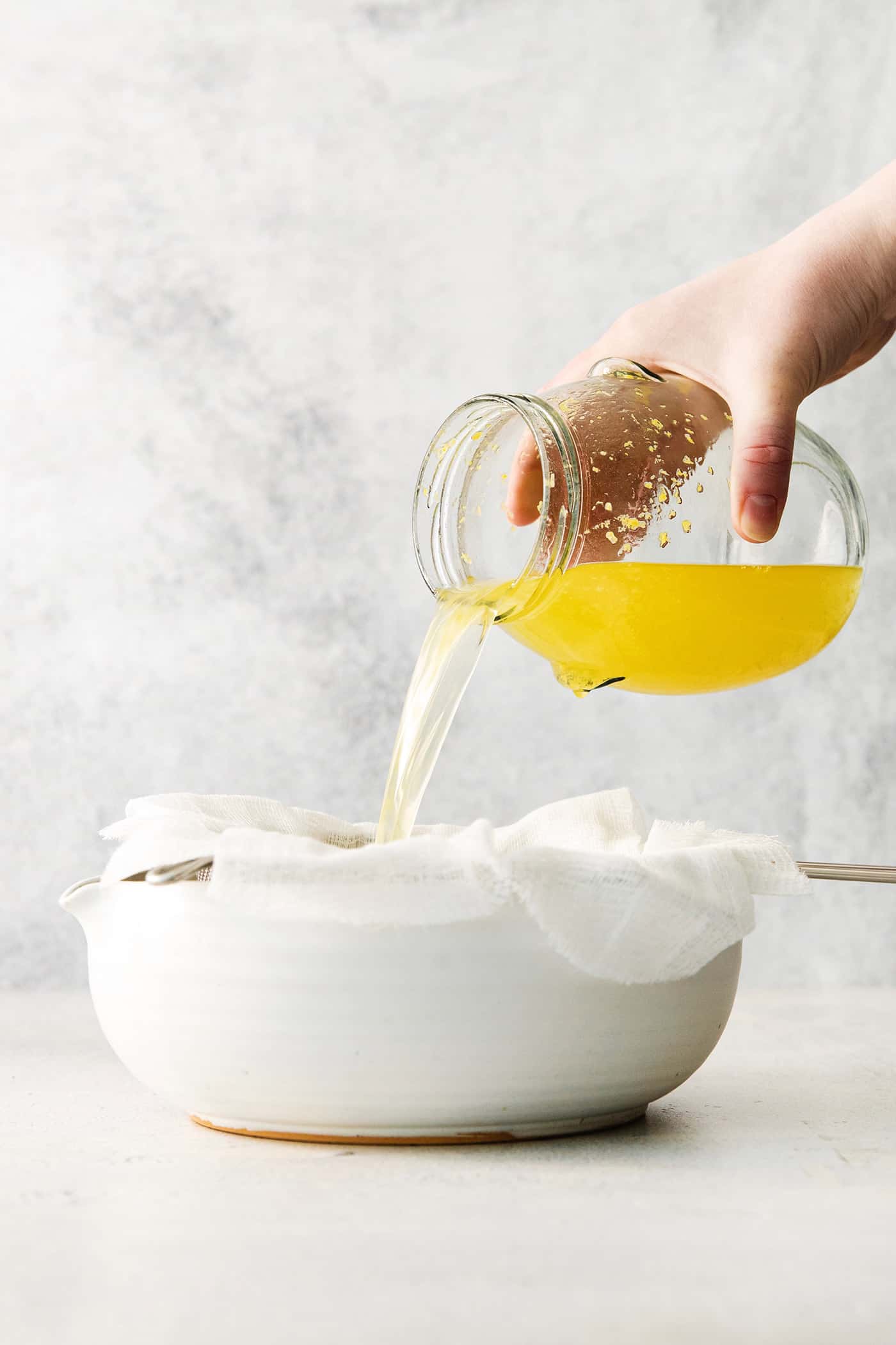 Pouring the lemon-vodka mixture through cheesecloth.