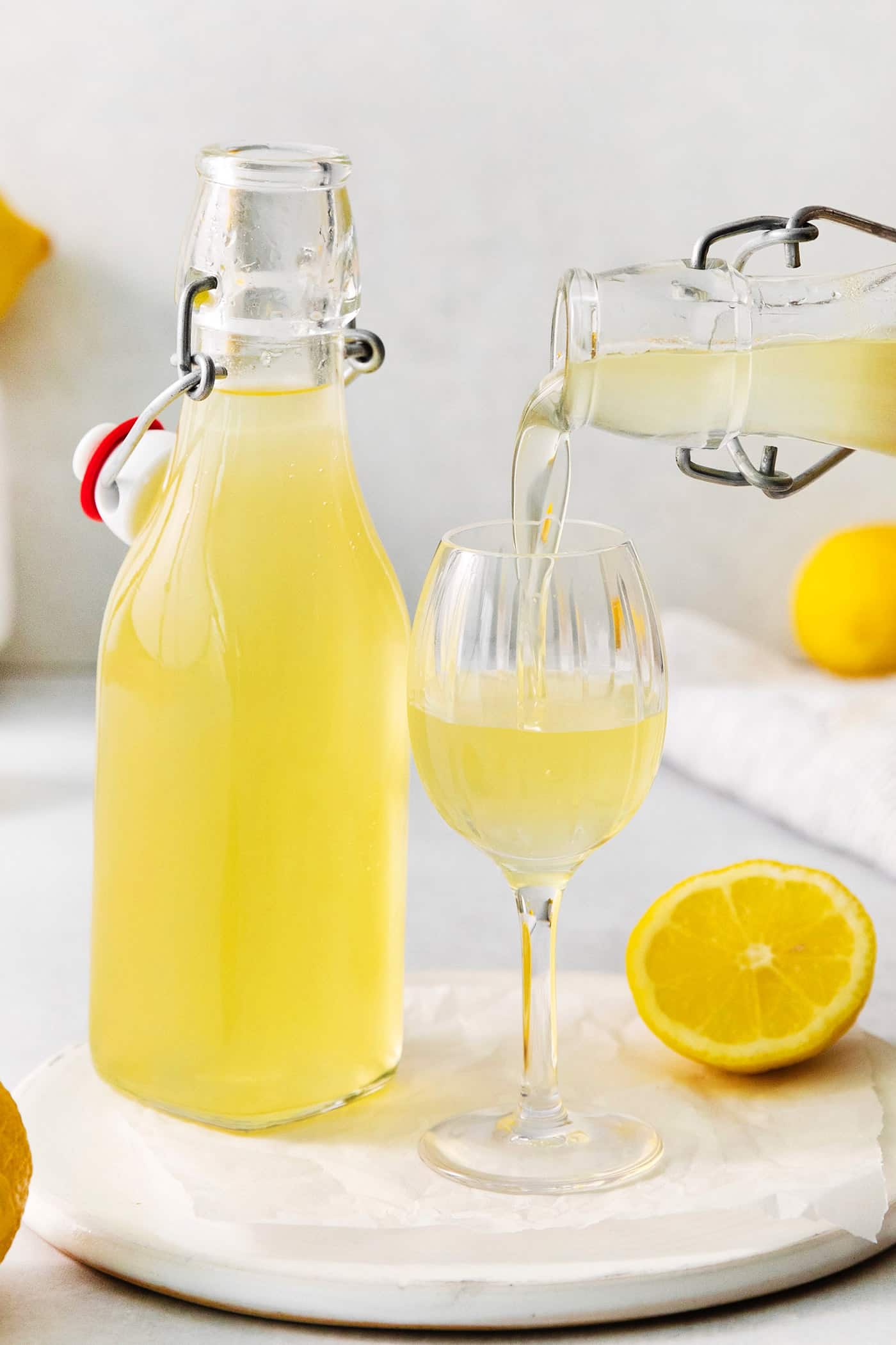A bottle of limoncello next to a glass of limoncello.