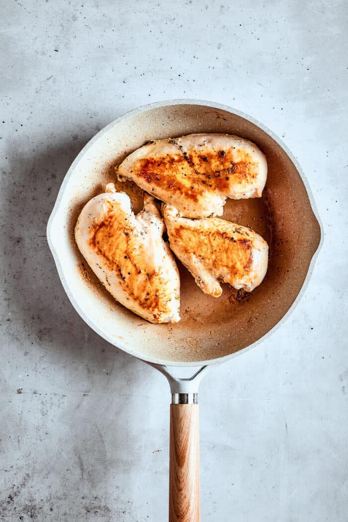Cooking chicken breast in a skillet.