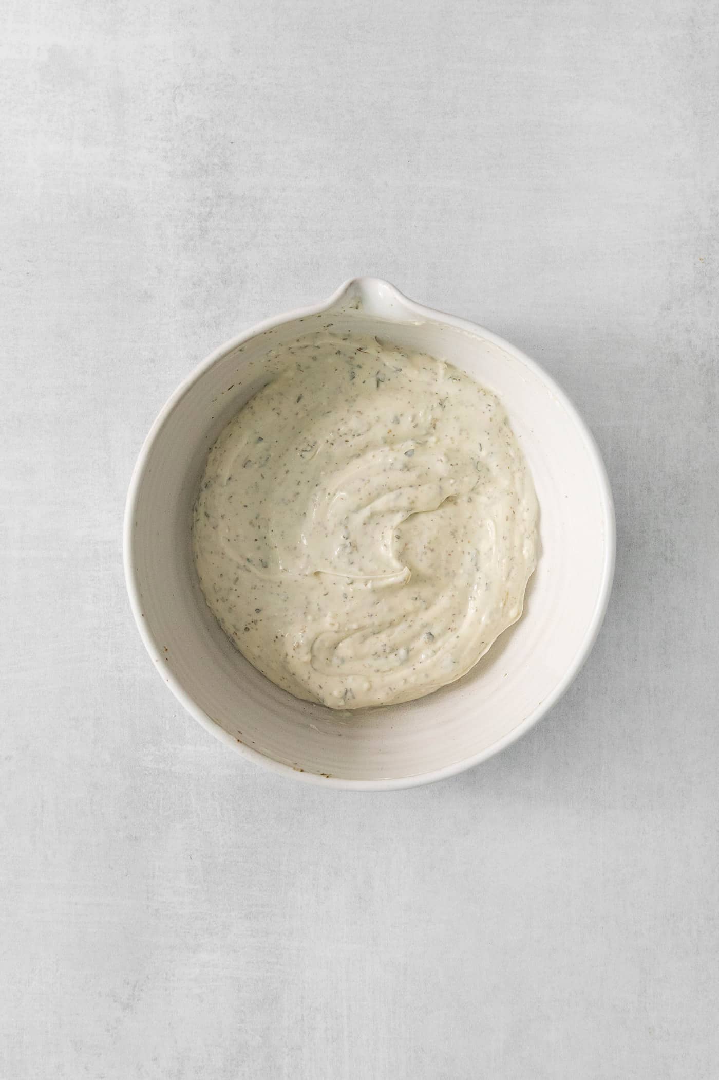 A white bowl of cream cheese spread.