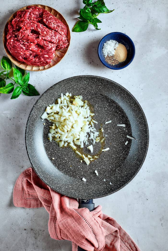 Garlic and onions are shown in a skillet.