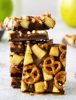 A close up of pieces of caramel apple bark with pretzels stacked on top of each other.
