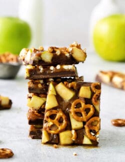 A close up of pieces of caramel apple bark with pretzels stacked on top of each other.