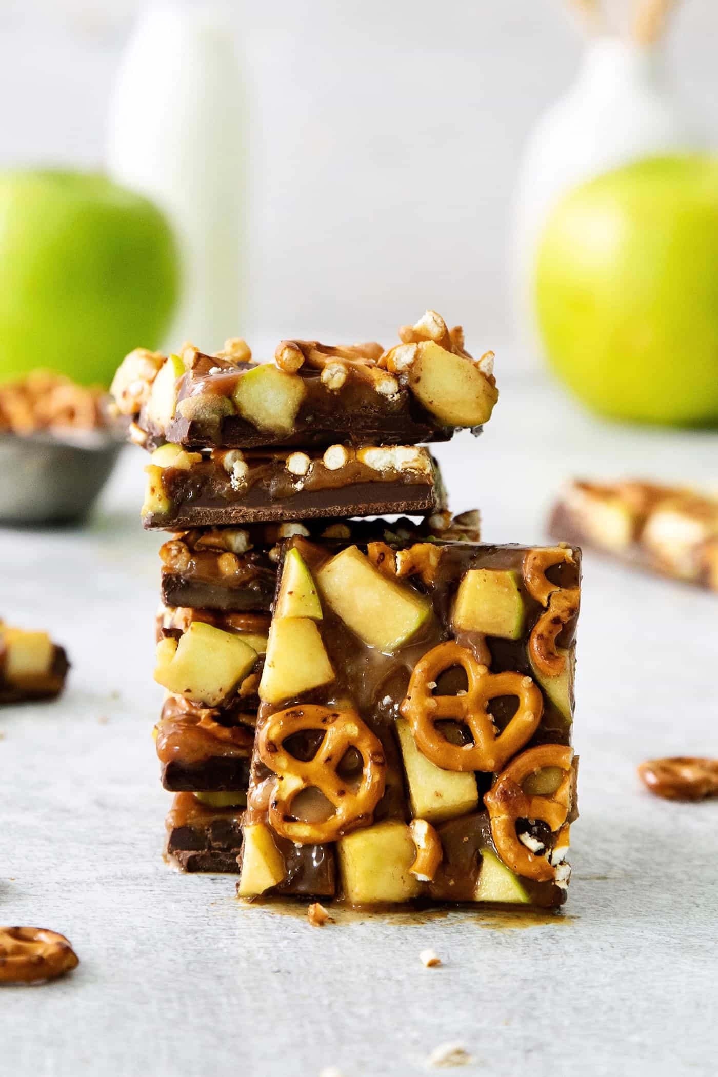 A close up of pieces of caramel apple bark with pretzels stacked on top of each other.