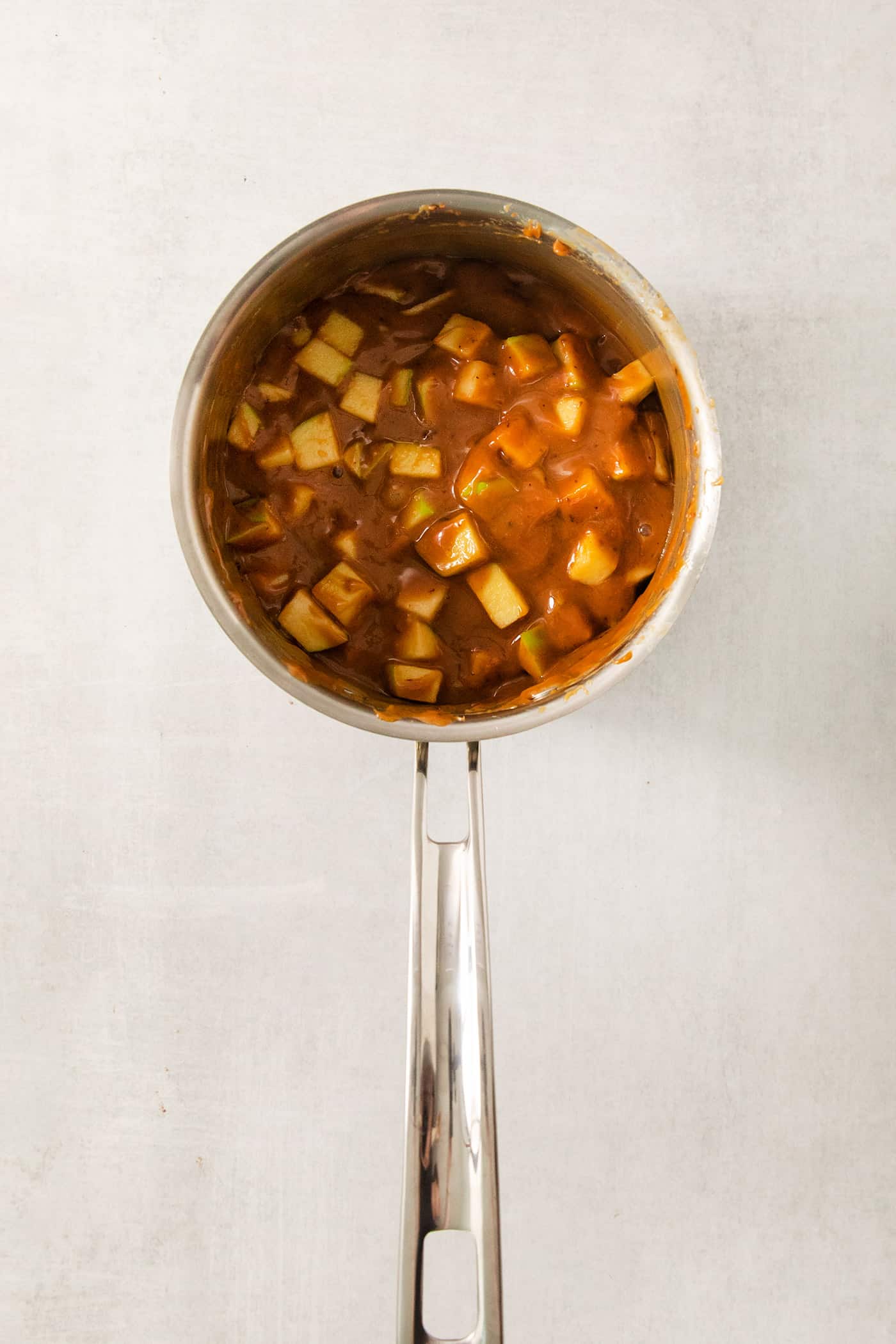 An overhead shot of a pot of caramel and chopped apples.