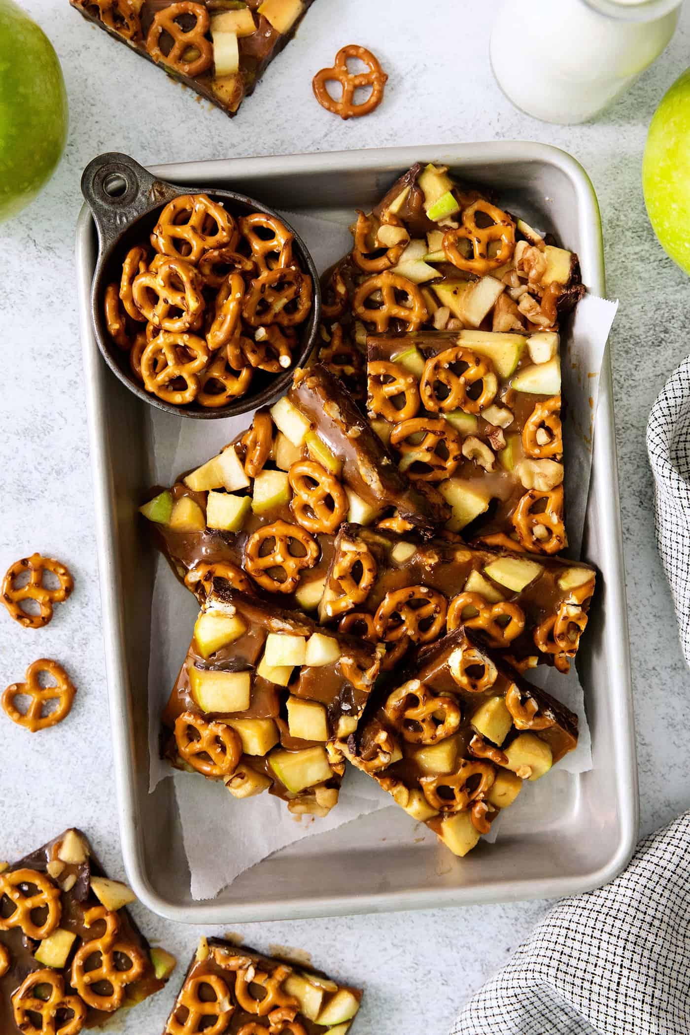 Cut up pieces of caramel apple bark are seen on a baking tray.