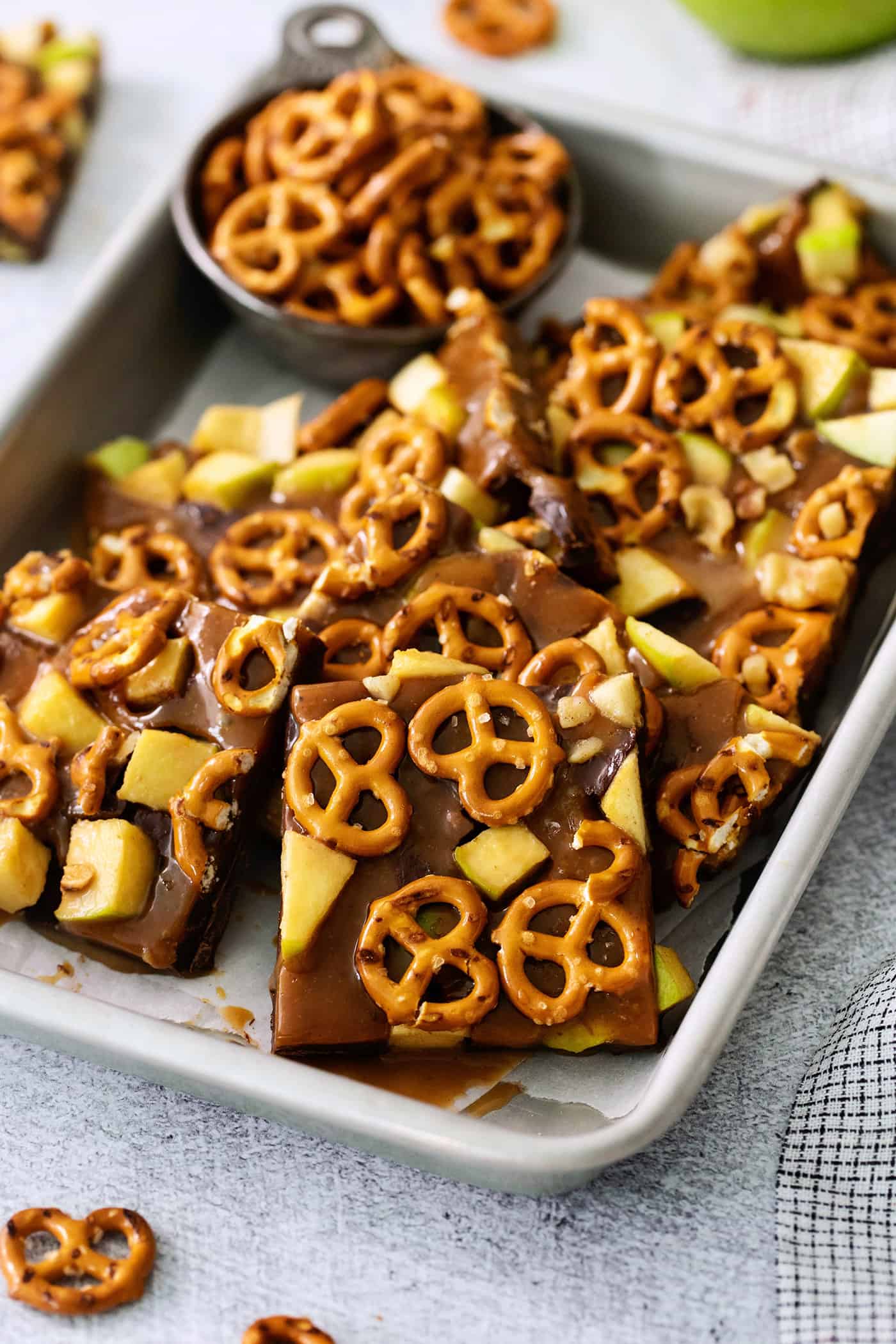 Cut up pieces of caramel apple bark are seen on a baking tray.