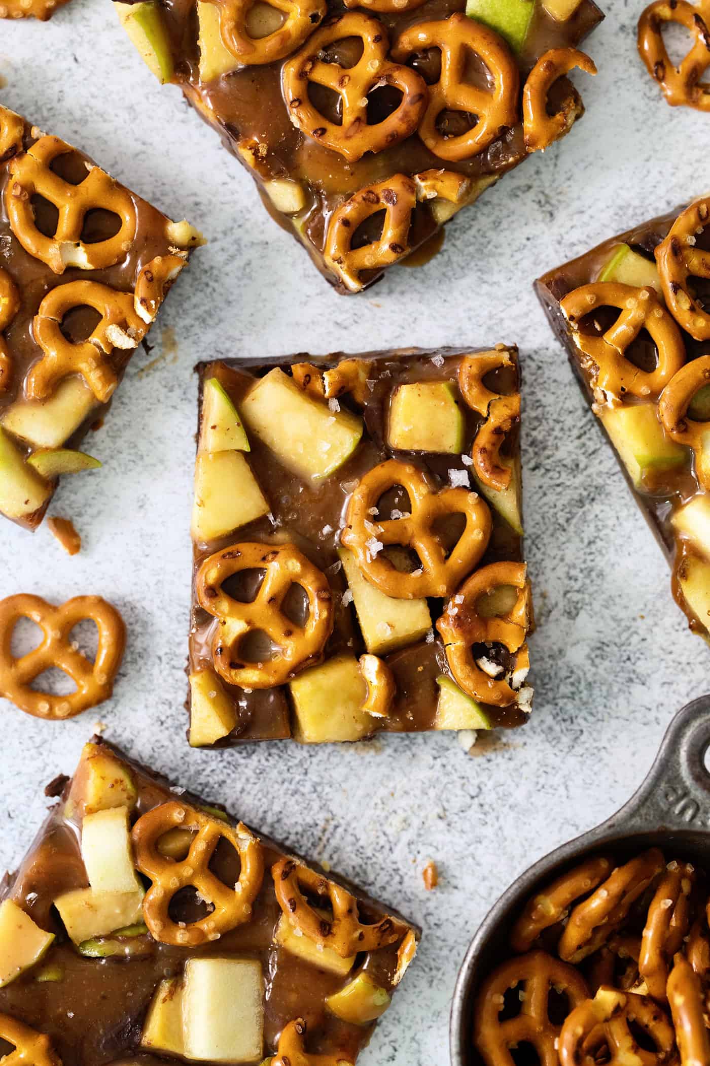 An overhead shot of pieces of caramel apple bark with pretzels on a white background.