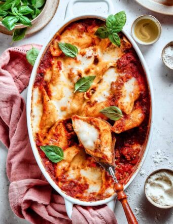 An overhead shot of a pan of stuffed shells with meat with a serving utensil.