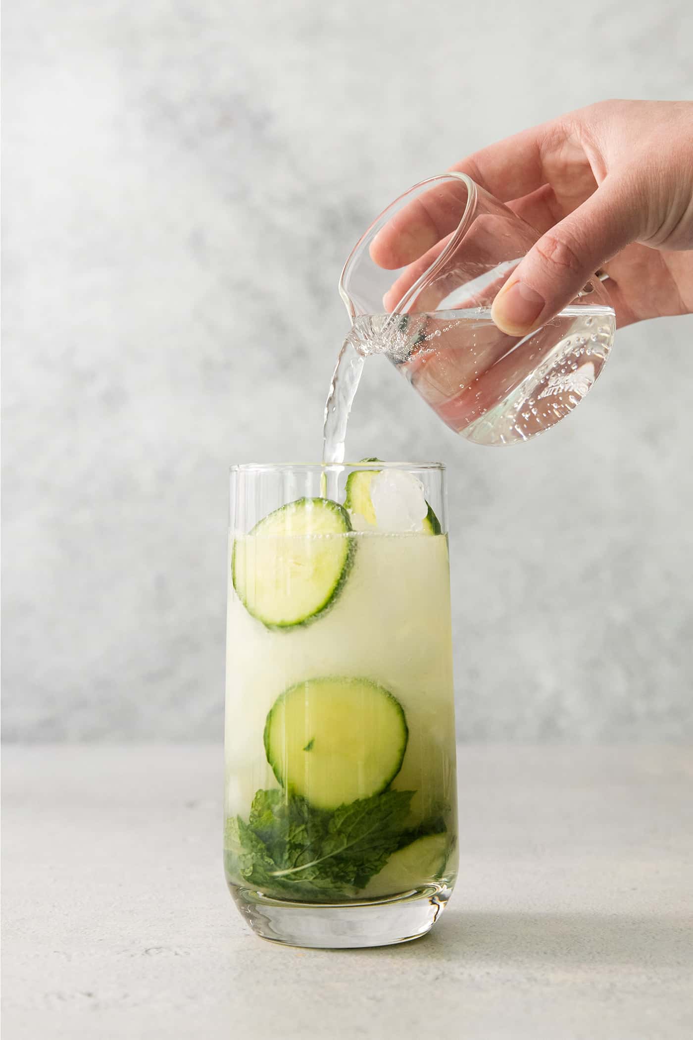 Topping a cucumber mojito with club soda.