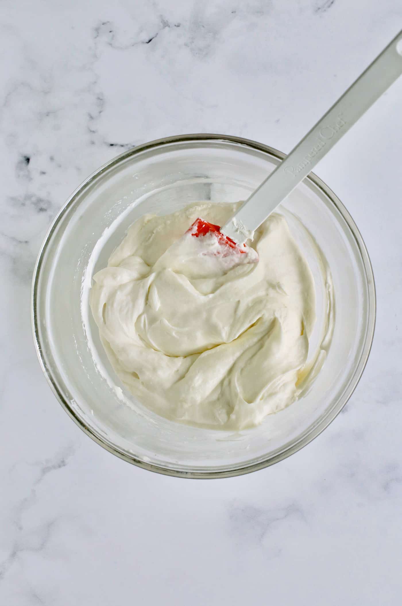 a clear bowl of whipped cream, cream cheese, sugar, and vanilla