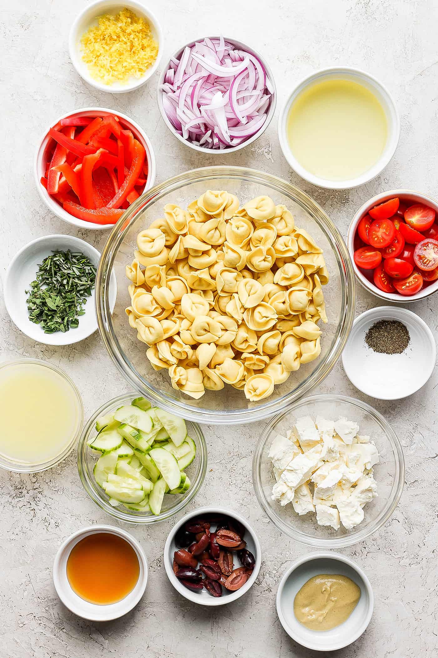 Ingredients needed for Greek tortellini salad: tortellini, vegetables, cheese, dressing.