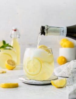 A bottle of prosecco is poured into a limoncello spritz.