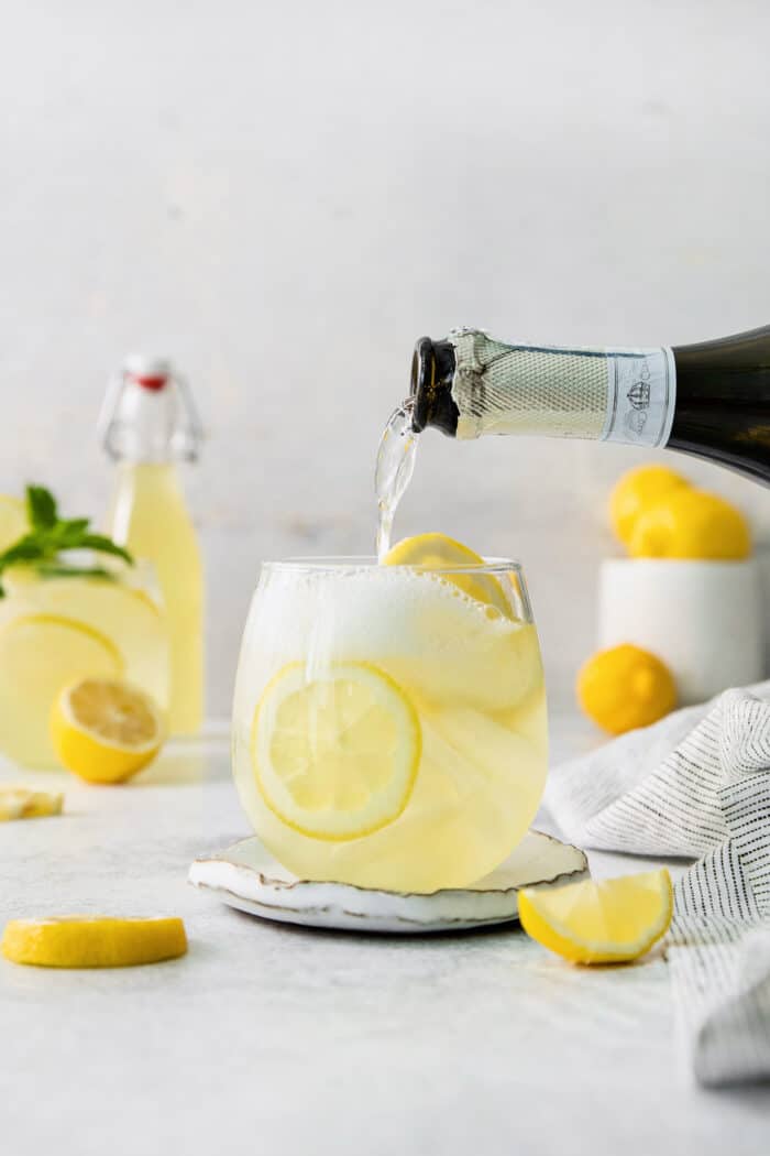 A bottle of prosecco is poured into a limoncello spritz.