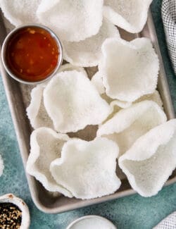 A tray of shrimp chips with a dish of chili sauce.