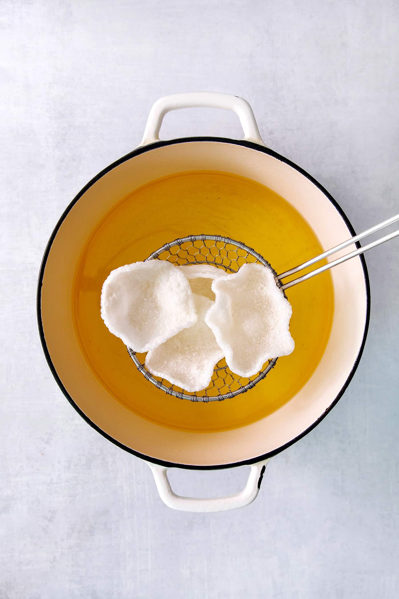 Prawn crackers are shown above a pot of hot oil.