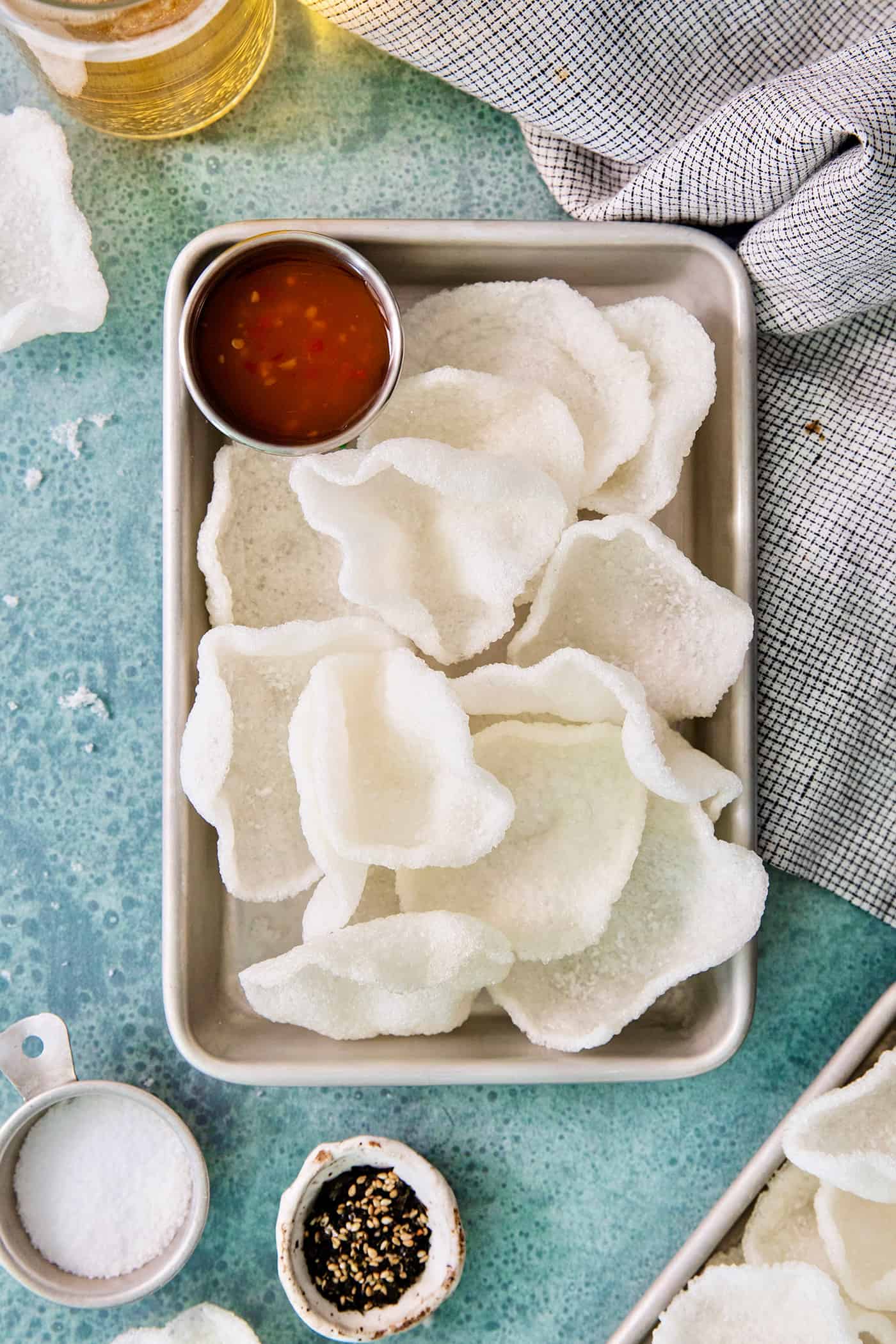 A tray of shrimp chips with a dish of chili sauce.