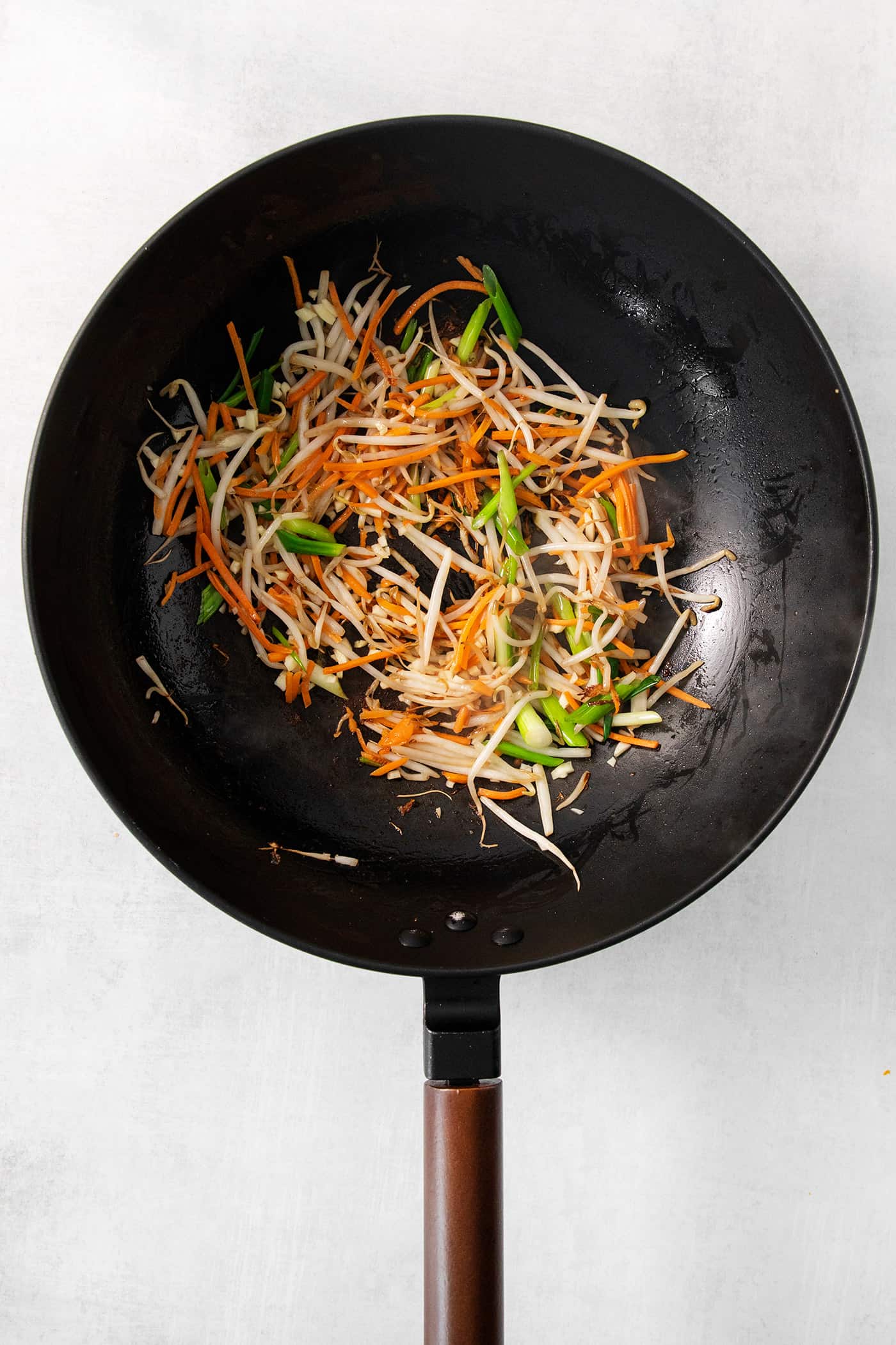 Vegetables are cooked in a black skillet.