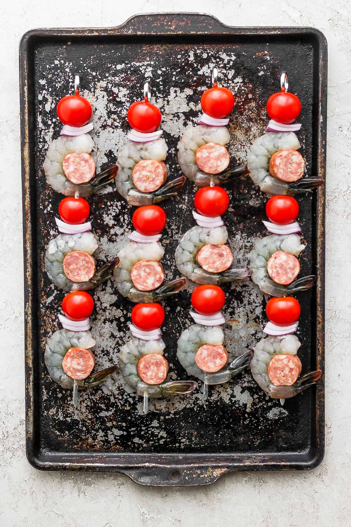 Shrimp and sausage kabobs are shown on a baking tray.