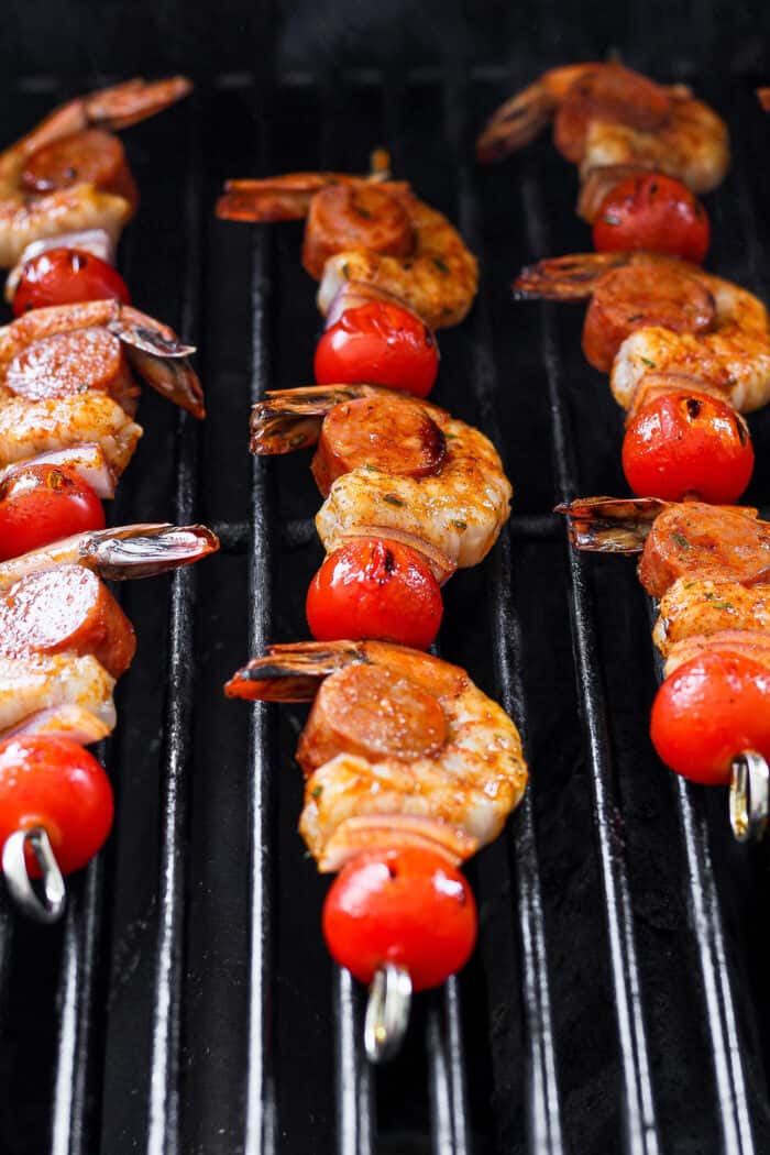 Shrimp and sausage kabobs cook on a grill.