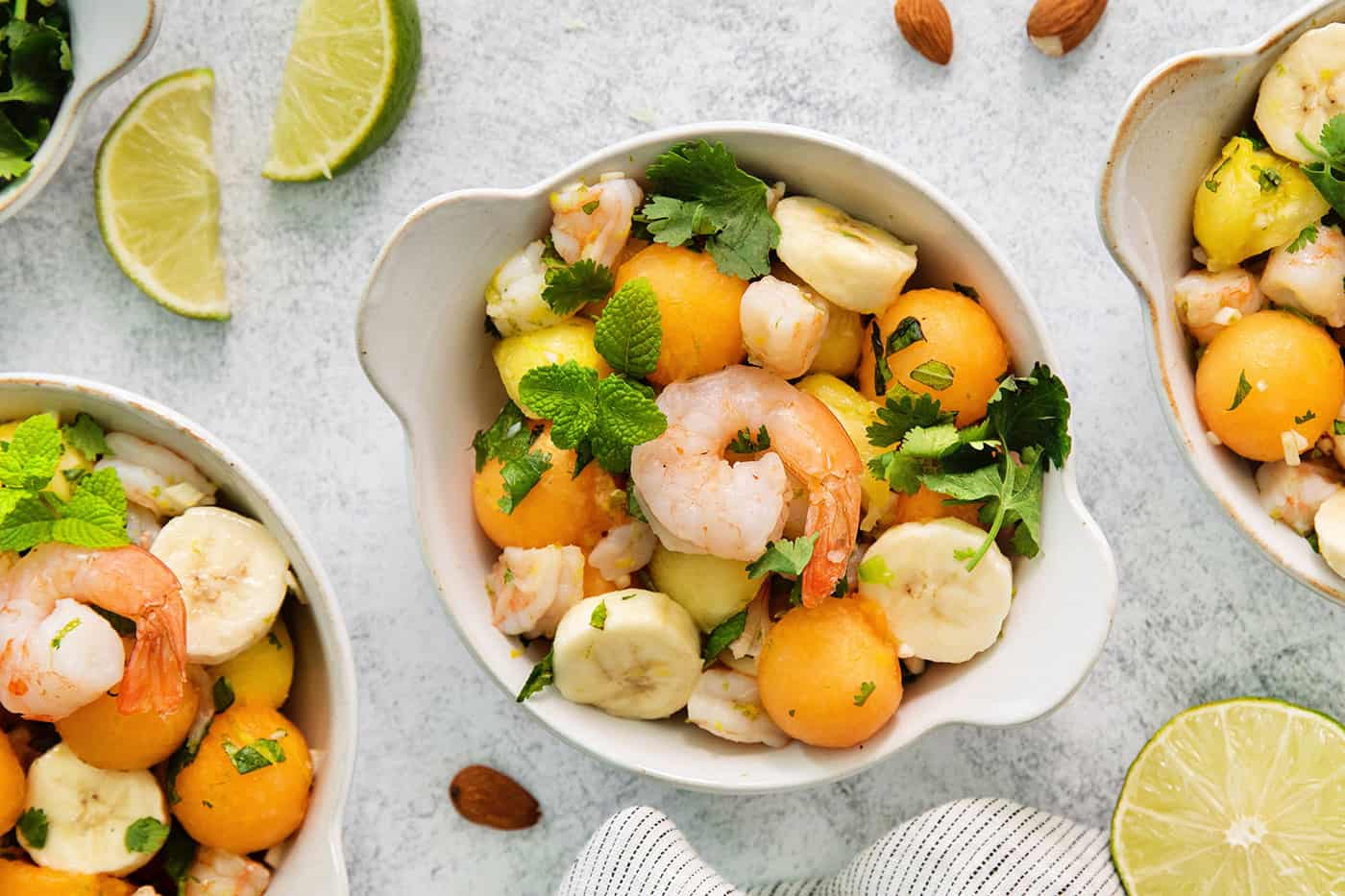 An overhead shot of bowls of tropical shrimp salad on a white background.