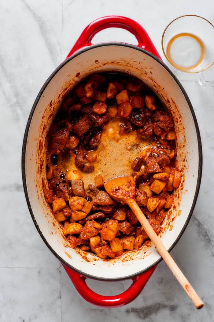 Spices are stirred into a pot of beef pot pie filling.