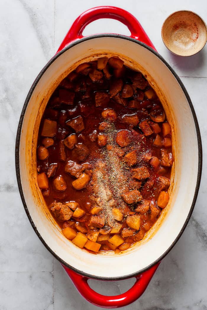 Spices are stirred into a pot of beef pot pie filling.