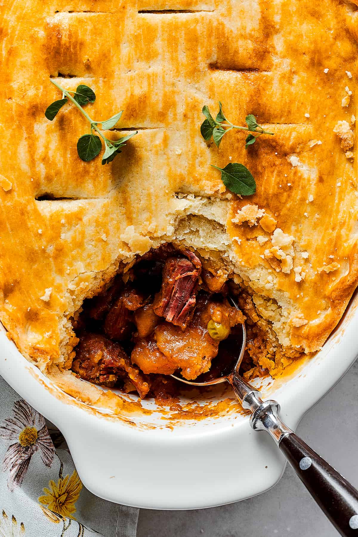 A beef pot pie is shown in a baking dish with a spoon.