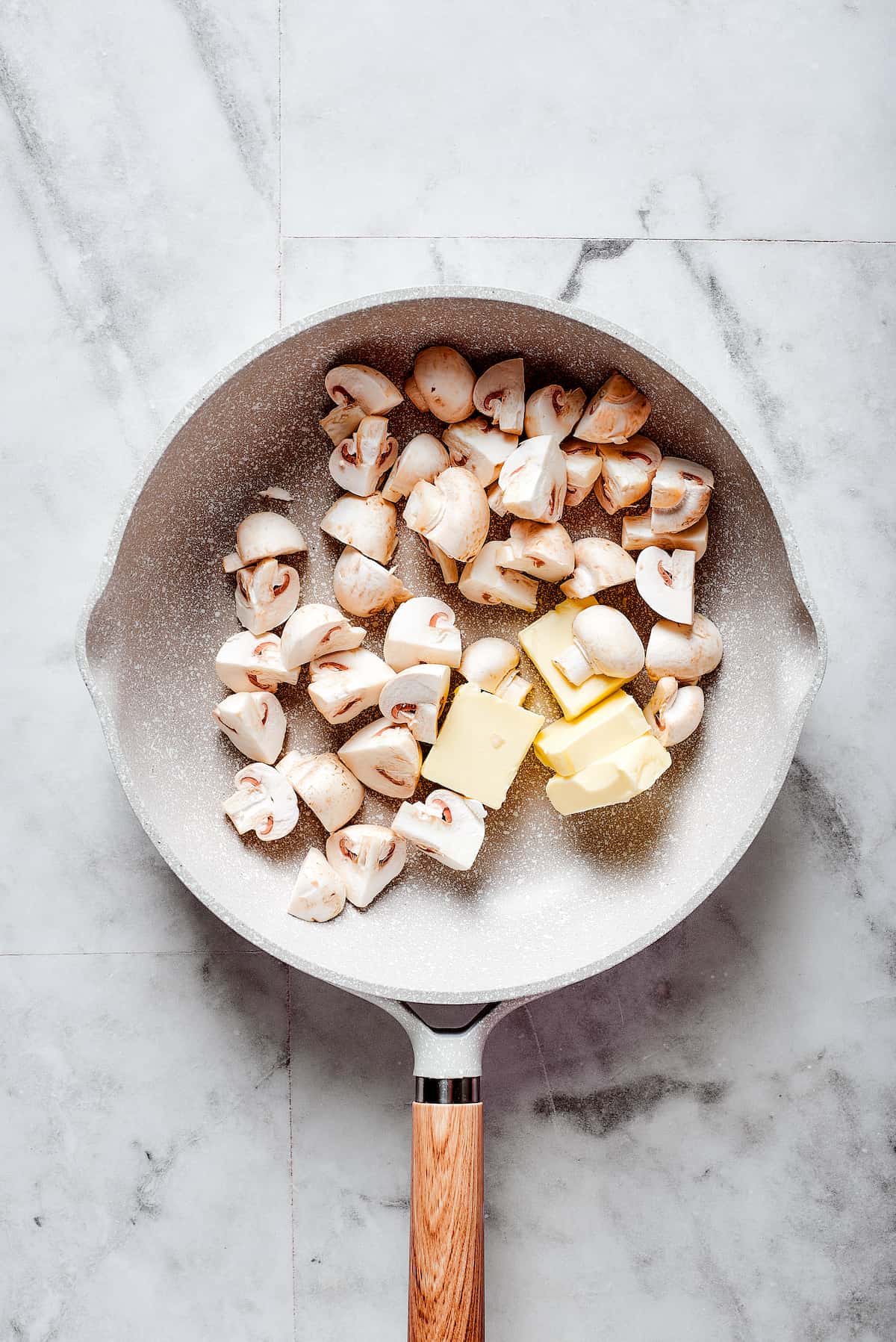 Mushrooms and butter are shown in a frying pan.