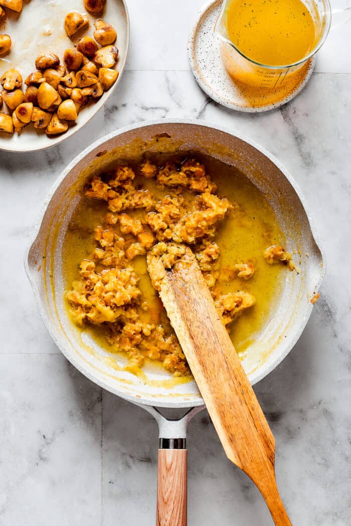 A wooden spoon stirs a pan of ingredients for Turkey A La King.