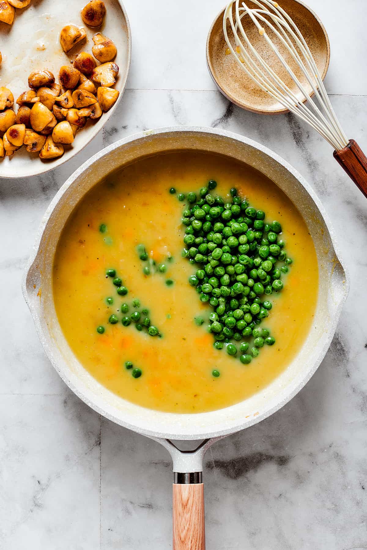 Chicken broth and peas are added to a pot,