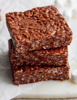 A stack of three chocolate rice krispie treats is shown on a white background.