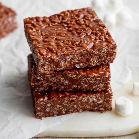 A stack of three chocolate rice krispie treats is shown on a white background.