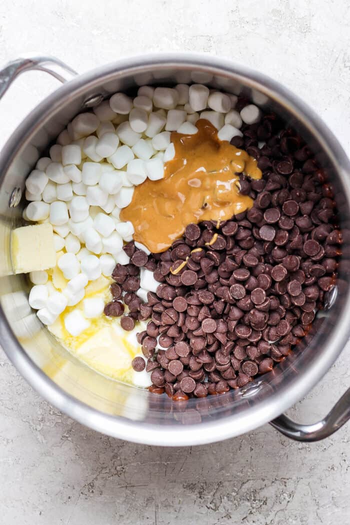 Mini marshmallows, chocolate chips, butter, and peanut butter are shown in a pot.